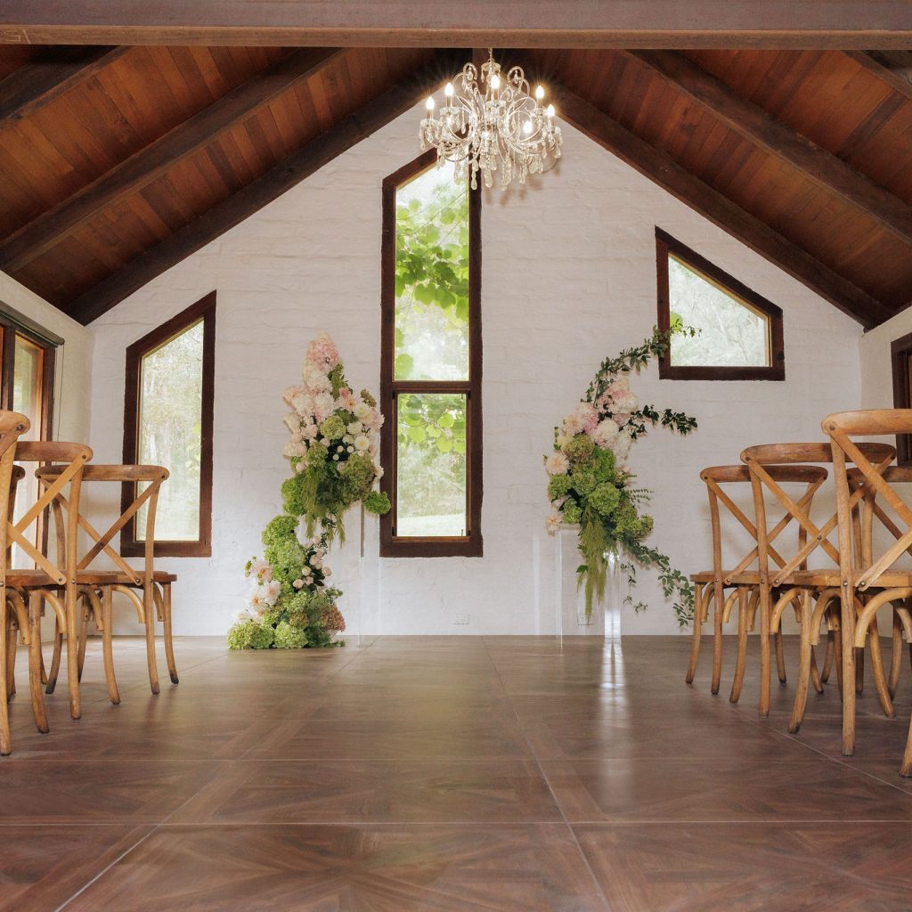 Rustic indoor wedding ceremony setup with floral arrangements