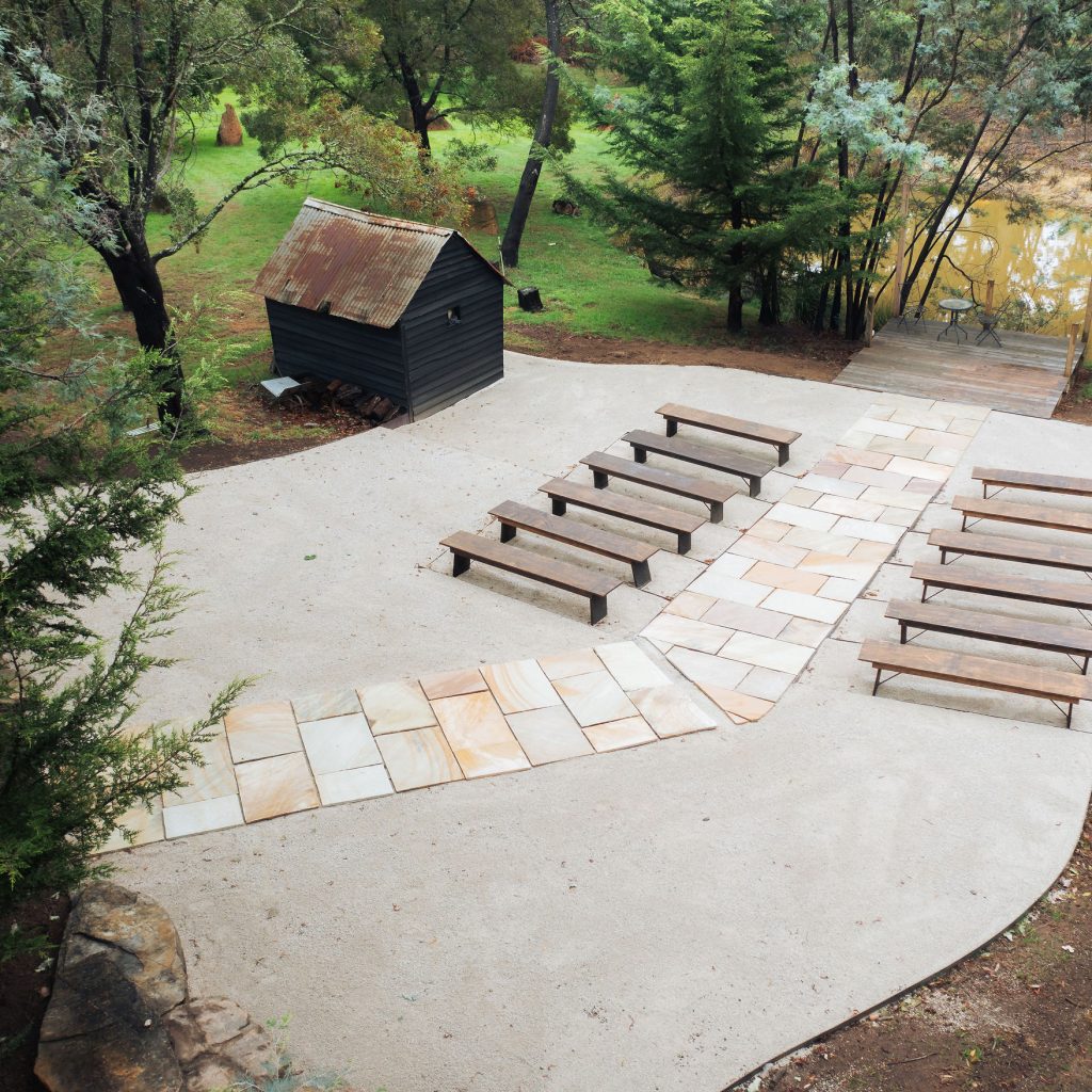 Outdoor wooden benches beside pond and rustic shed